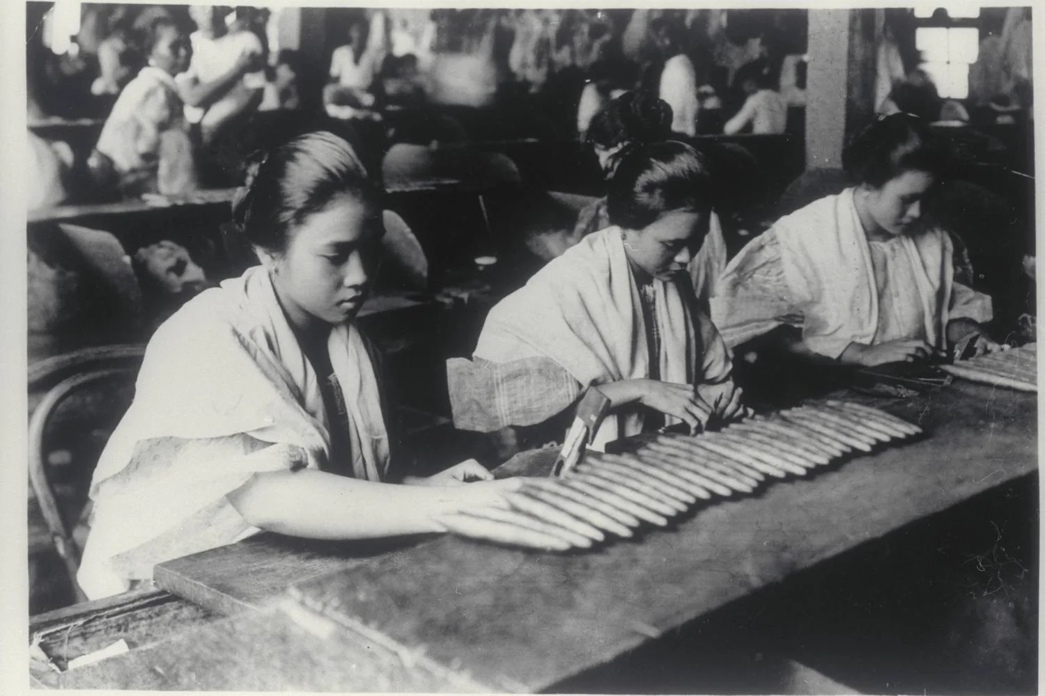 Cigar rollers at a wooden bench in Manila, archive photograph